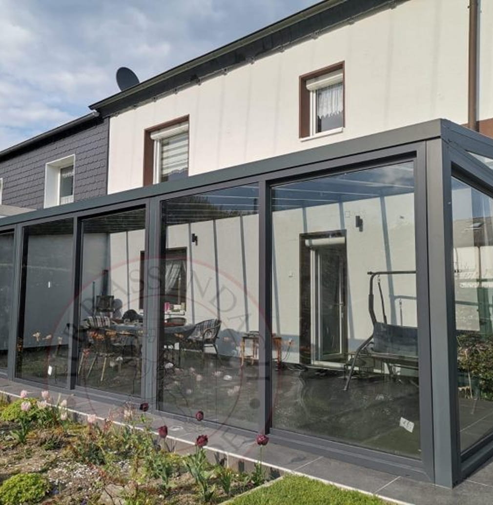 Angebauter Kaltwintergarten aus anthrazitfarbenem Aluminium mit großflächigen Glas-Schiebeelementen an einem Wohnhaus